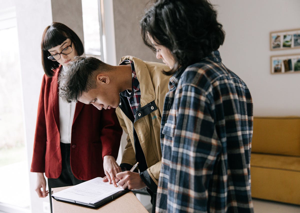 Couple signing home purchase documents with real estate agent - buying a home in Belleville Ontario Gulliver Team