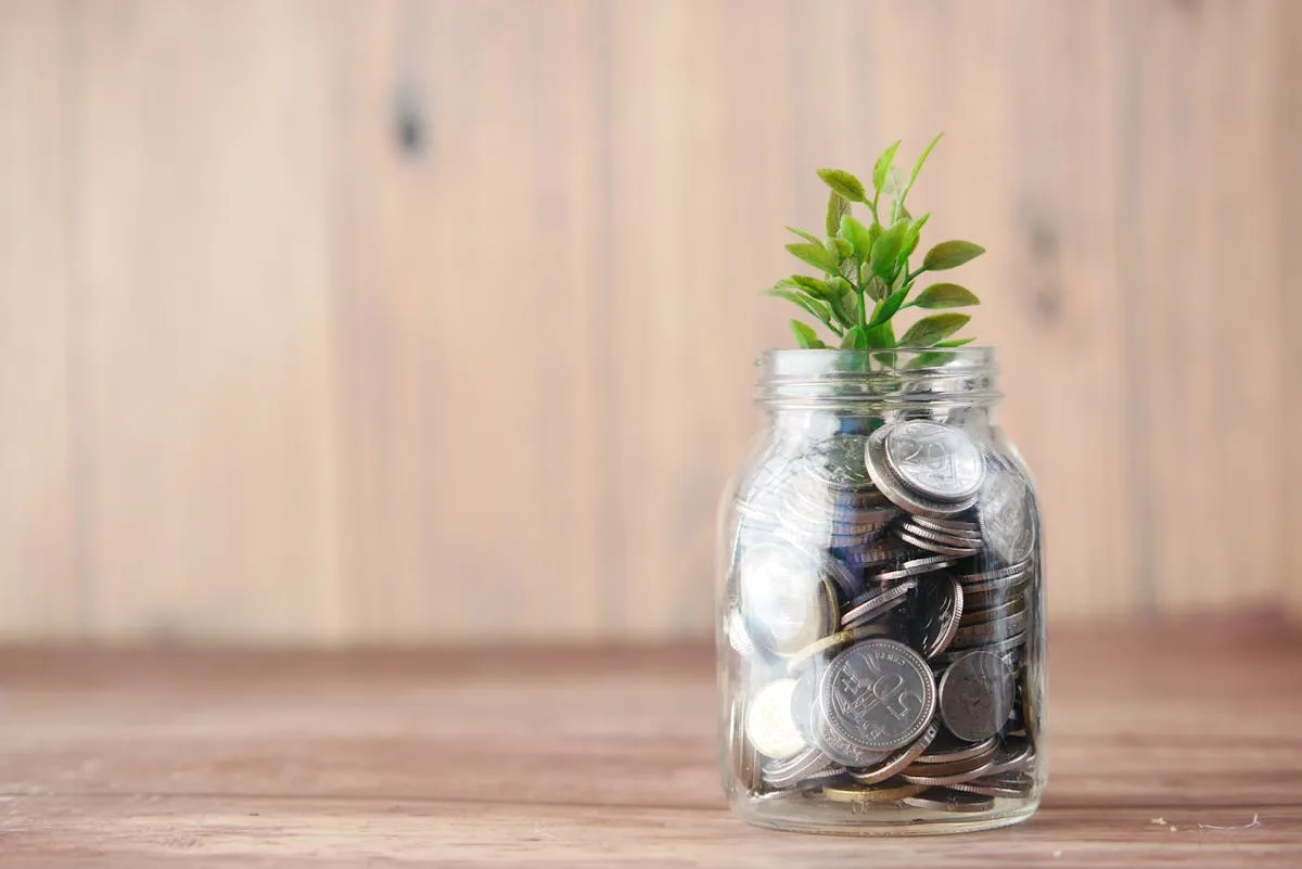 Glass jar with coins and growing plant representing financial planning growth and savings - Shannon Neely Financial