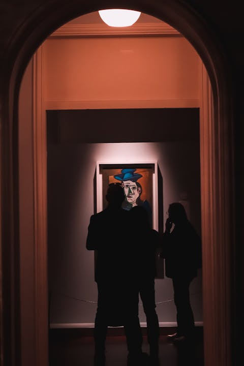 Visitors silhouetted against colourful abstract paintings in an art gallery corridor - Halcyon Days Ultra Vivid exhibition
