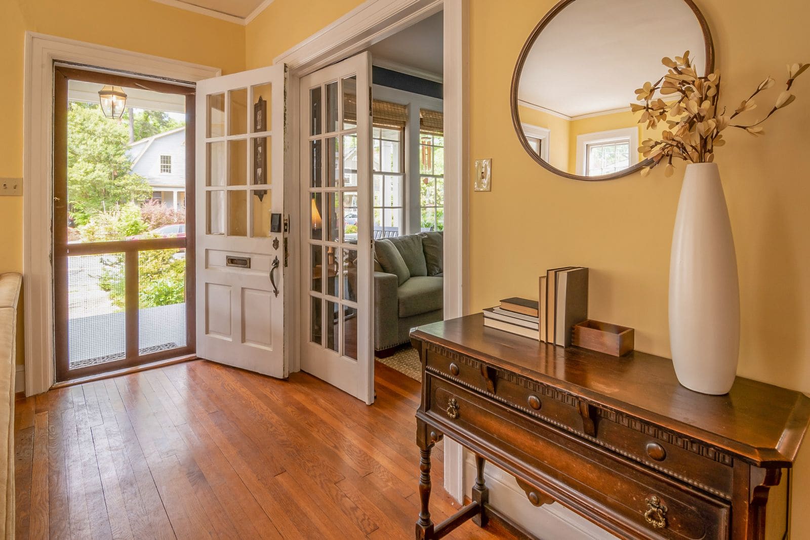 Sunny front entryway with open doors, hardwood floor and a wooden console table
