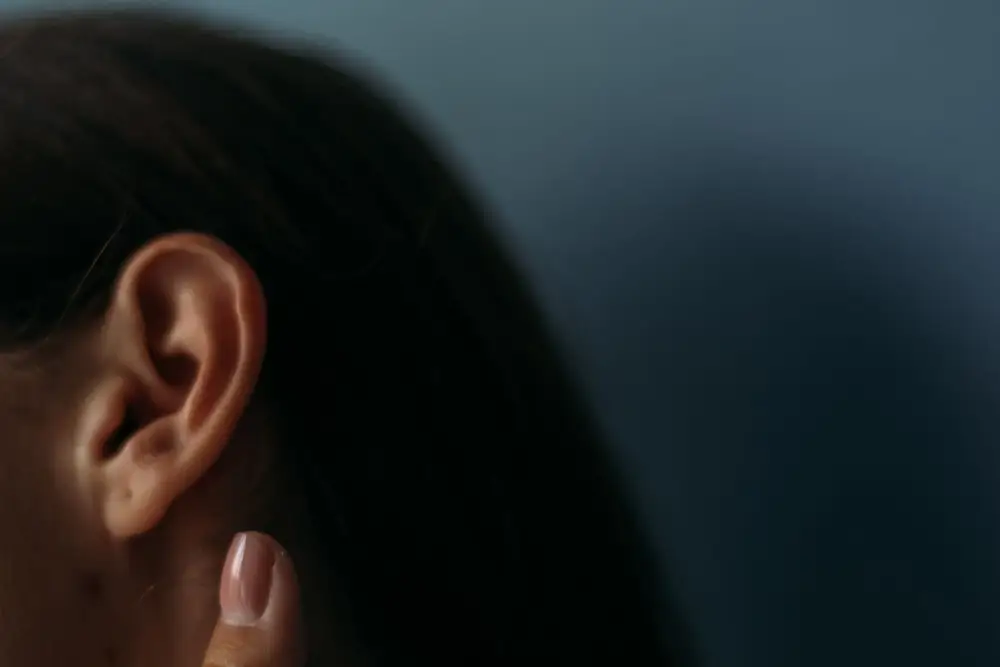 Close-up of a woman's ear with her fingertip resting just below it