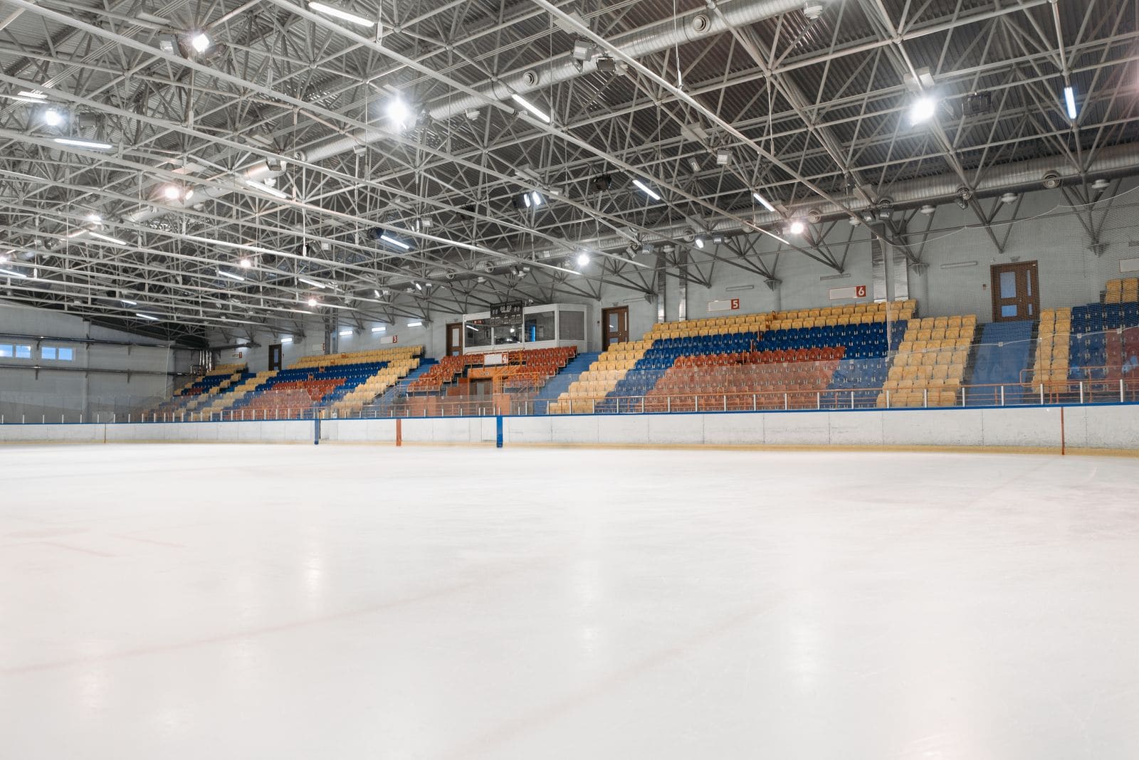 Empty, brightly lit indoor ice rink with colourful stands