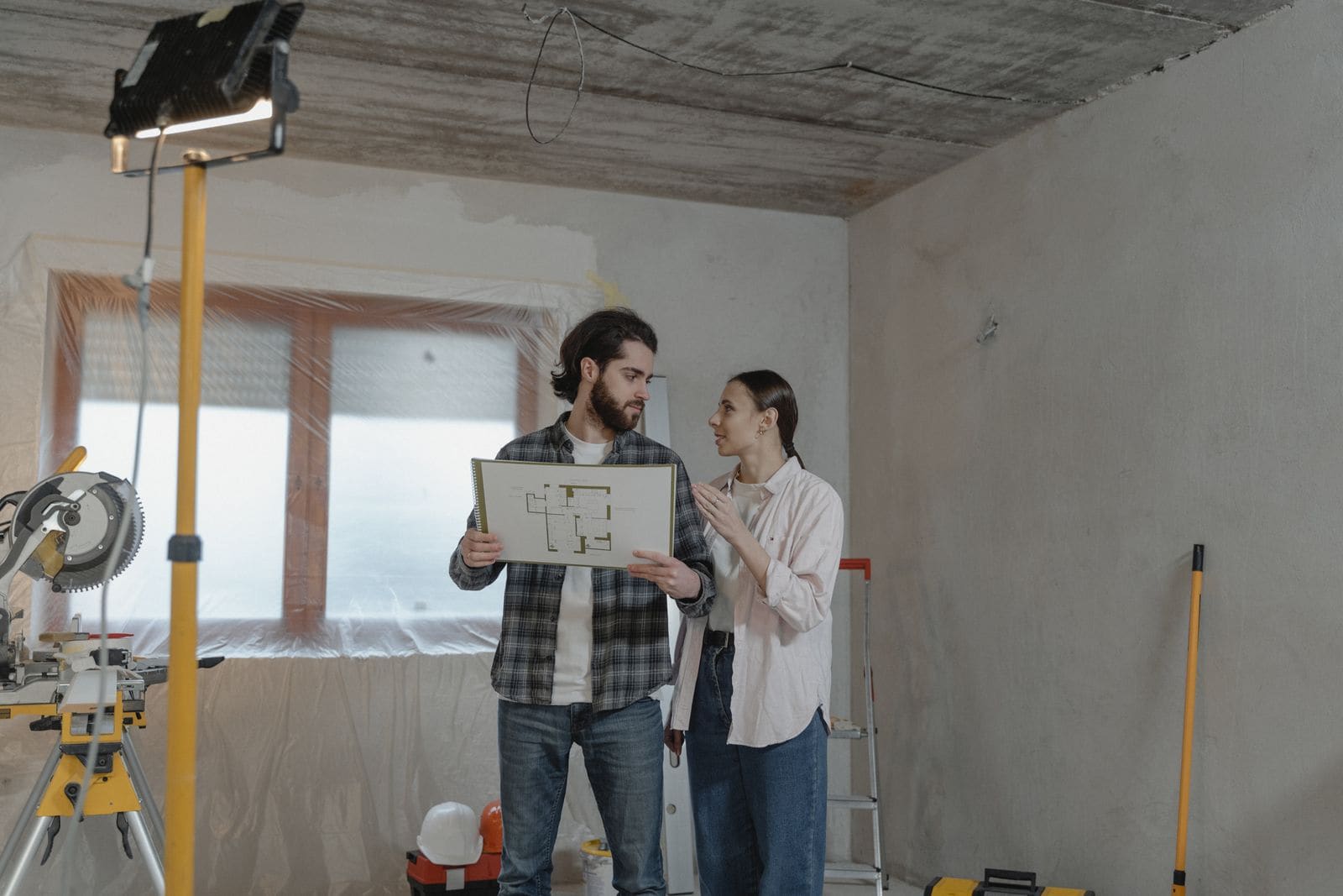 Couple studying a floor plan in a room being renovated